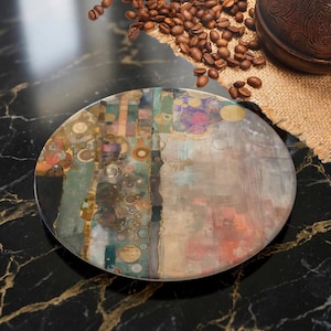 May include: A circular coaster featuring an abstract design with a mix of teal, gold, beige, and deep red tones. The surface displays intricate geometric patterns, including small circles and linear elements, creating a textured, layered appearance.