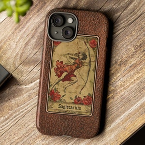 May include: A brown leather phone case with a vintage tarot card design featuring Sagittarius. The card depicts a woman in a red dress holding a bow and arrow.