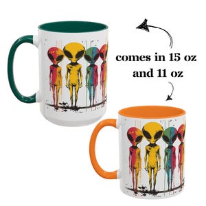 Puede incluir: Dos tazas de caf&eacute; de cer&aacute;mica blanca con un borde interior verde y naranja. Ambas tazas presentan un gr&aacute;fico colorido de cinco extraterrestres con pintura goteando. El texto "comes in 15 oz and 11 oz" est&aacute; impreso en la imagen.
