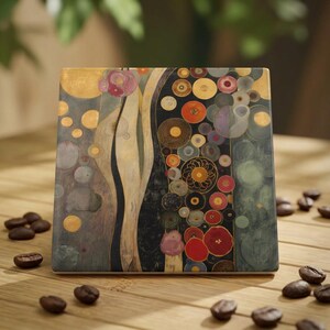 May include: A square coaster featuring a decorative pattern of gold, black, red, and muted green circles and flowing lines. The design includes intricate circular motifs and organic shapes arranged in a vertical composition across the surface.