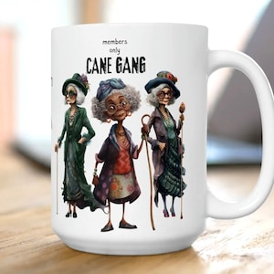 May include: White ceramic mug with a graphic of three older women with canes and the text "members only CANE GANG".