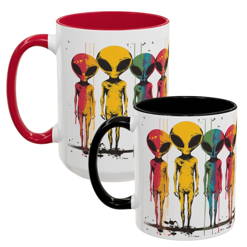 Puede incluir: Dos tazas de cer&aacute;mica blanca con bordes negros y rojos. Las tazas presentan un gr&aacute;fico colorido de cinco extraterrestres con cuerpos de diferentes colores y ojos negros. Los extraterrestres est&aacute;n de pie en fila con los brazos a los lados. El fondo es blanco con salpicaduras de pintura negra.