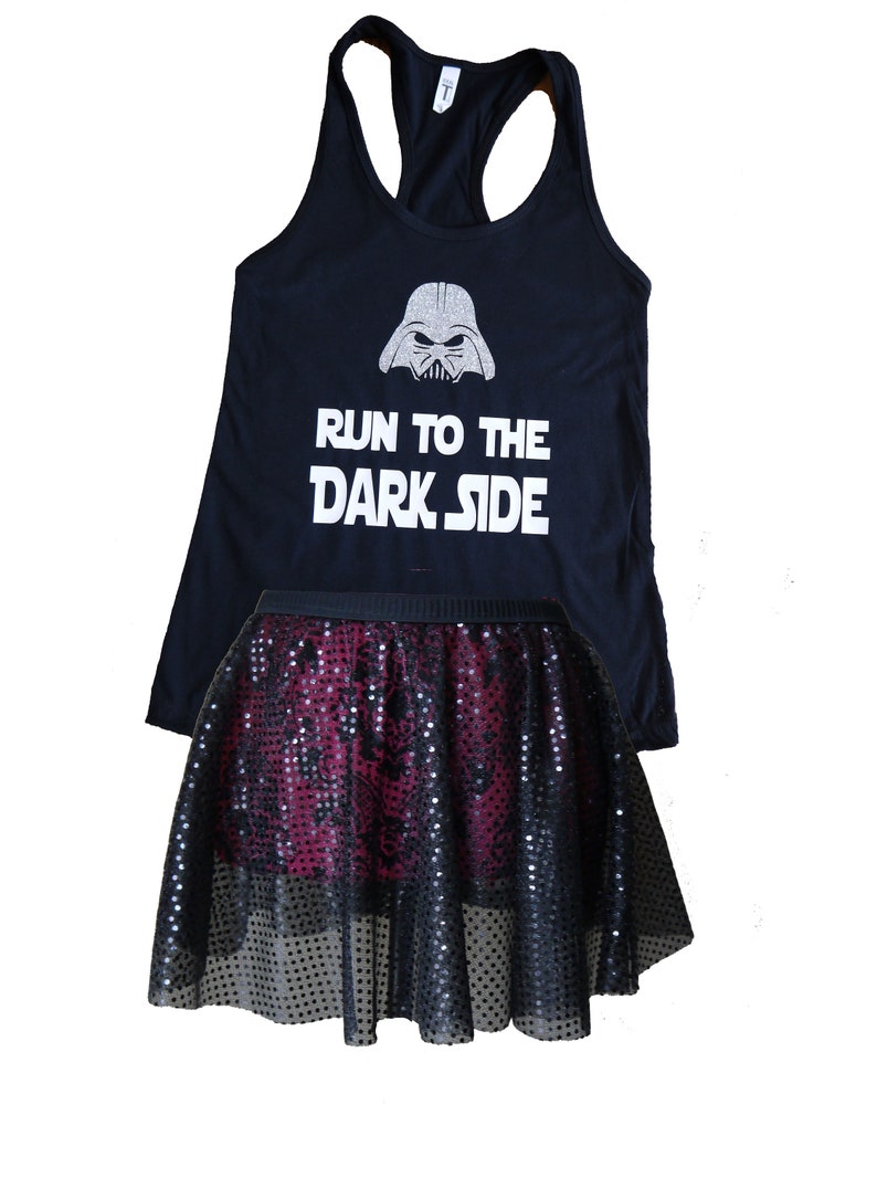 Puede incluir: Camiseta negra de tirantes con un gr&aacute;fico de Darth Vader en purpurina plateada y el texto "Run to the Dark Side". Una falda de lentejuelas negra y burdeos se superpone a la camiseta.