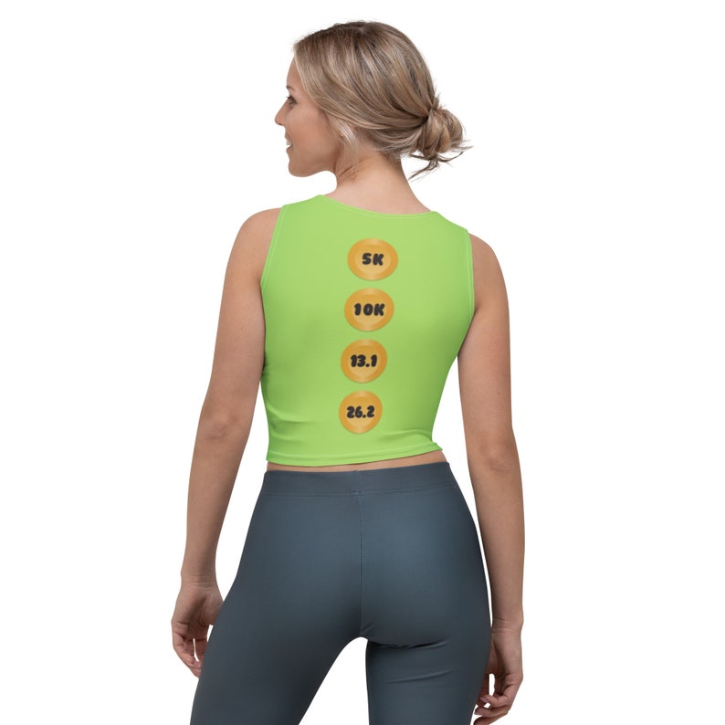 Puede incluir: Un top corto sin mangas de color verde lima con cuatro c&iacute;rculos dorados en la espalda. Los c&iacute;rculos tienen los n&uacute;meros 5K, 10K, 13.1 y 26.2 impresos en negro.
