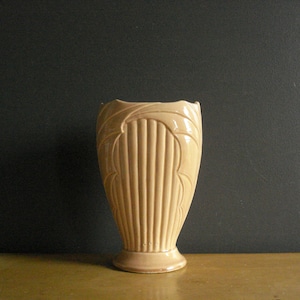 以下が含まれることがあります： フルーテッドデザインと丸いベースを持つ薄いピンクのセラミック花瓶