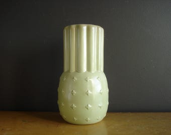 May include: A light green ceramic vase with a textured, pineapple-like design. The vase has a smooth, glossy finish.