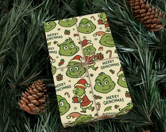 May include: A wrapped gift with a festive Grinch-themed wrapping paper. The paper features Grinch faces, Santa Grinch illustrations, candy canes, and the text "Merry Grinchmas". The gift is tied with twine and set against a backdrop of pine needles and pine cones.