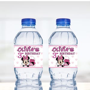 May include: Two clear plastic water bottles with pink and white labels. The labels feature a cartoon image of Minnie Mouse and the text "Olivia's 3rd Birthday".