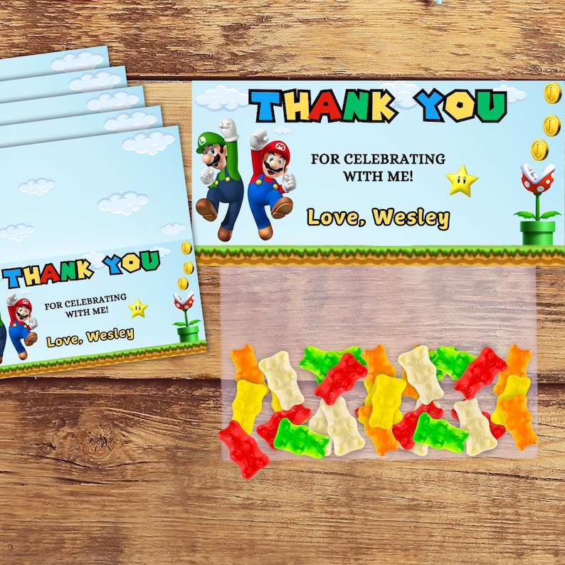 May include: Thank you favor bags with a blue background and a cartoon image of Mario and Luigi. The bags are filled with colorful gummy candies. The text on the bag reads "Thank You for celebrating with me! Love, Wesley".