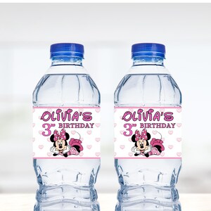May include: Two clear plastic water bottles with pink and white labels. The labels feature a cartoon image of Minnie Mouse and the text "Olivia's 3rd Birthday".