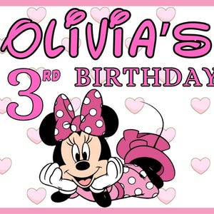 May include: Pink banner with a white background and a pink heart pattern. The banner says "Olivia's 3rd Birthday" in pink letters. There is a cartoon image of Minnie Mouse in a pink dress with white polka dots.