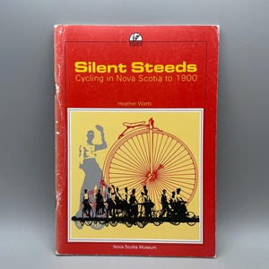Könnte beinhalten: Ein Buch mit dem Titel "Silent Steeds: Cycling in Nova Scotia to 1900" mit rotem Einband und gelbem Hintergrund. Das Cover zeigt ein großes Fahrradrad, Silhouetten von Radfahrern und eine Frau. Das Logo des Nova Scotia Museums ist sichtbar.
