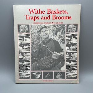 May include: A book titled "Withe Baskets, Traps and Brooms" with the subtitle "Traditional crafts in Nova Scotia." The cover features a black and white photo of a man holding a woven basket. The book has a grey border with red text.