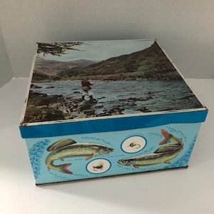 Vintage tin box with photo of fly fisherman in lid with fish and lures on sides