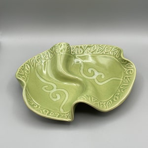 Peut inclure: Un plat de service en céramique vert avec une forme ondulée organique et un motif floral blanc autour du bord.