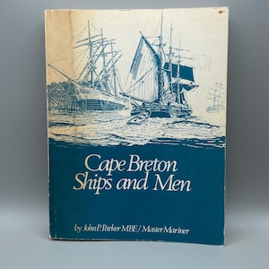 Peut inclure: Un livre vintage intitulé "Cape Breton Ships and Men" avec une illustration bleue et blanche de voiliers. La couverture présente le titre et le nom de l'auteur en texte blanc sur fond bleu.