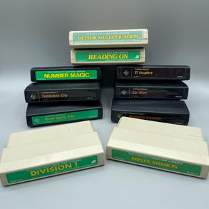 May include: A selection of vintage Texas Instruments Solid State Cartridges, featuring titles such as "Meteor Multiplication," "Reading On," and "Division 1." The cartridges have green and white labels.