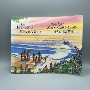 May include: A children's book cover with a watercolor illustration of a group of people in traditional clothing standing on a beach. The book title is "The Voyage of Wood Duck" and the subtitle is "Tan Teli Kaqasimiila'asis Malsiks" by Maxine Trottier and Patsy Macaulay McKinnon.