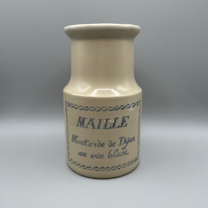 Puede incluir: Un tarro de mostaza de cerámica con una etiqueta azul y blanca que dice "Maille Moutarde de Dijon au vin blanc".