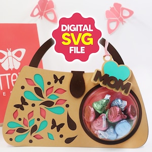 Puede incluir: Una caja de regalo en forma de bolso de mano de color beige con una ventana circular transparente llena de caramelos envueltos. El bolso tiene un asa marrón y está decorado con mariposas recortadas y diseños florales en color turquesa y rosa. Una etiqueta que dice "MOM" cuelga del asa.