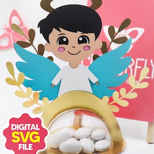 May include: A decorative angel-themed favor box with a clear dome containing white candies. The angel has blue wings, a gold halo, and a smiling face. The text "DIGITAL SVG FILE" is displayed on a pink background.