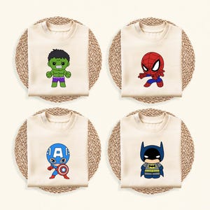 May include: Four cream-colored t-shirts, each featuring a different cartoon superhero: Hulk, Spider-Man, Captain America, and Batman. The shirts are arranged on round, woven placemats, creating a playful and colorful display.