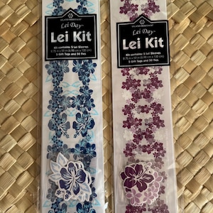 May include: Two Island Heritage Lei Kit packages in clear plastic sleeves. One kit features blue hibiscus floral patterns, the other purple. Each kit contains 5 lei sleeves measuring 2.75 in x 52 in, 5 gift tags, and 50 ties for assembly.