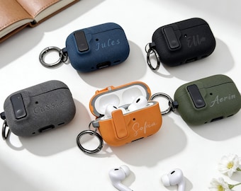 May include: Several personalised AirPod cases in shades of navy, black, grey, olive green, and orange. Each case is inscribed with a name, like "Jules" or "Sofia", and has a silver carabiner. Two white AirPods are also shown.