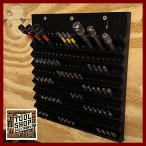 May include: A black, wall-mounted tool organizer with multiple slots and angled shelves. Various tools, including sockets and screwdriver bits, are stored in the organizer. The Tool Shop Solutions logo is visible in the lower left corner.