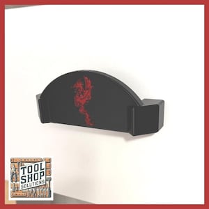 May include: A black, semi-circular tool holder with a red dragon design. The holder has a rectangular base and is mounted on a white surface. The Tool Shop Solutions logo is in the lower left corner.