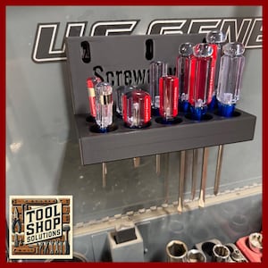 May include: A black screwdriver organizer with the word "Screwdriver" printed on it. The organizer holds several screwdrivers with red and clear handles. The image also shows the "Tool Shop Solutions" logo.