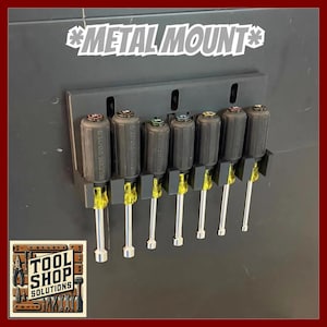 May include: A black Metal Mount tool holder with six screwdrivers. The screwdrivers have black handles, yellow shafts, and silver tips. The text "METAL MOUNT" is above the screwdrivers. The Tool Shop Solutions logo is in the lower left corner.