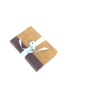 May include: A brown book with a textured cover is tied with a light blue ribbon.