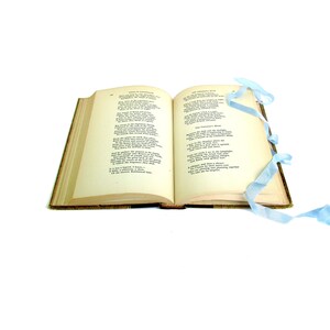 May include: An open book with a light blue ribbon bookmark. The pages contain poetry with the titles "The Heart of the Hills" and "The Chimney Sweeper".