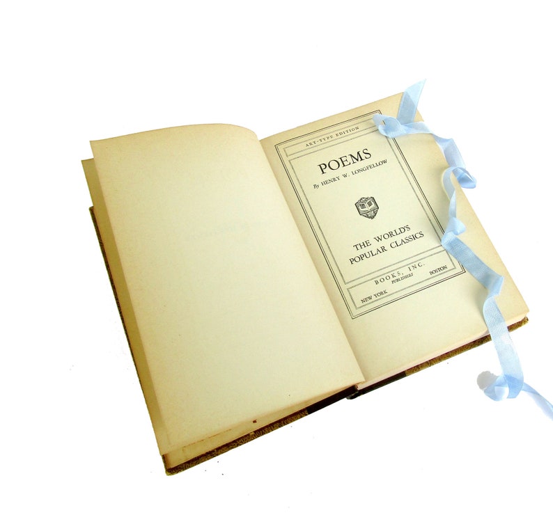 May include: An open book with a light blue ribbon bookmark. The book is titled "Poems" by Henry W. Longfellow. The book is part of "The World's Popular Classics" series.