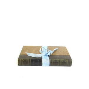 May include: A brown leather-bound book with a light blue ribbon tied around it. The book has the title "The Writings of William Shakespeare" printed on the spine.