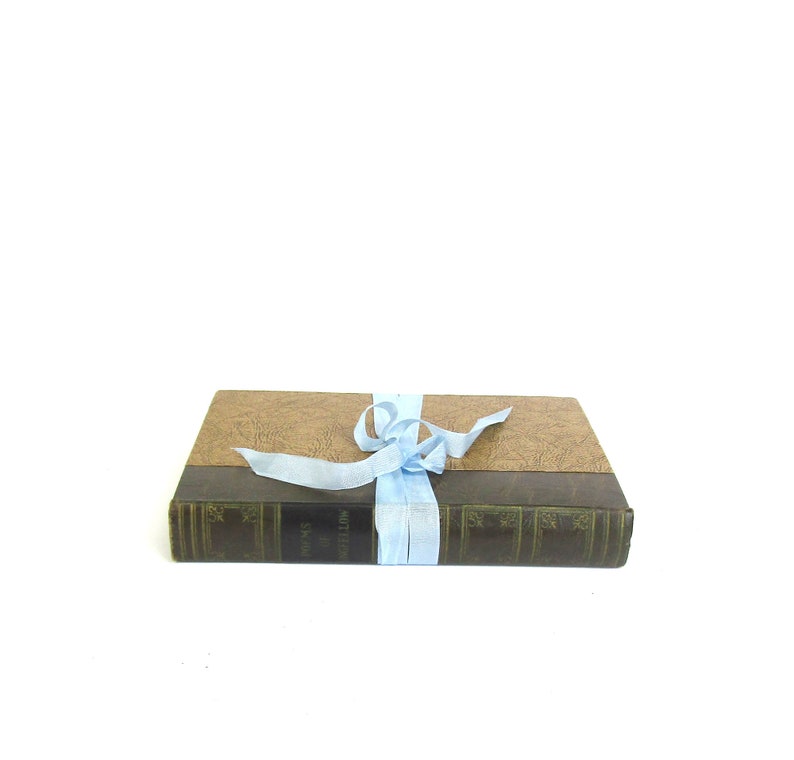 May include: A brown leather-bound book with a light blue ribbon tied around it. The book has the title "The Writings of William Shakespeare" printed on the spine.
