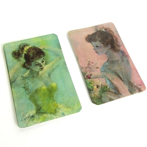 May include: Two vintage cards with watercolor illustrations of women. The card on the left features a woman in a green dress with her hair up. The card on the right features a woman in a blue dress with her hair down. Both cards are signed "Cyprian".