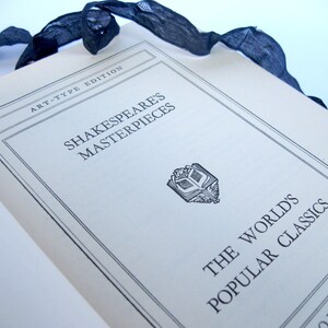 May include: A white book with the title "Shakespeare's Masterpieces" and the subtitle "The World's Popular Classics" printed on the cover. The book is part of the "Art-Type Edition" series.