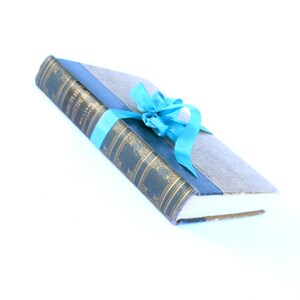 May include: A blue book with gold lettering and a blue ribbon tied around it. The book is titled "Shakespeare's Masterpieces" by William Shakespeare.