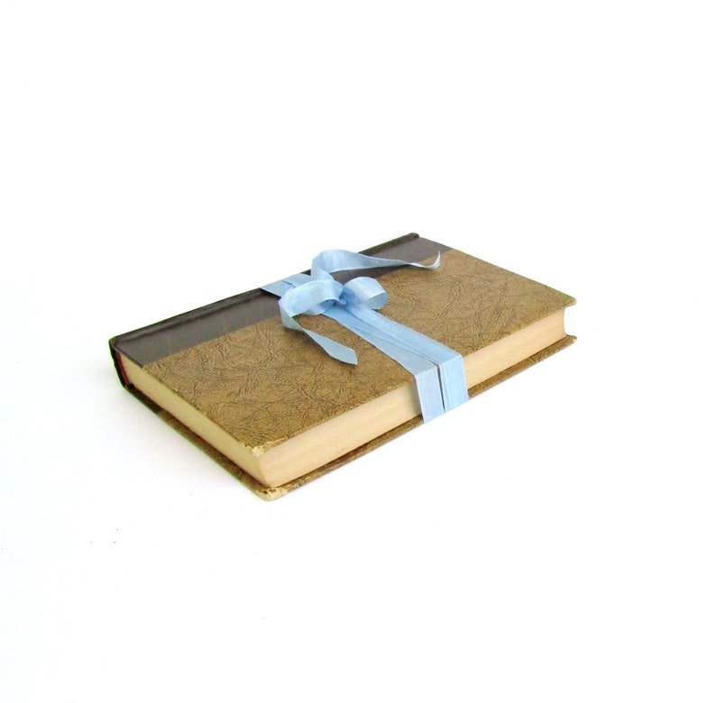 May include: A brown book with a light brown cover and a light blue ribbon tied around it.