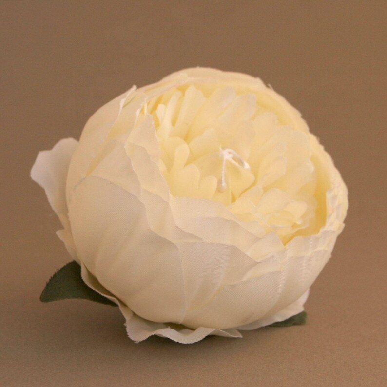 May include: A single, cream-coloured artificial peony flower with a ruffled, layered appearance. The flower is made of fabric and has a realistic look.