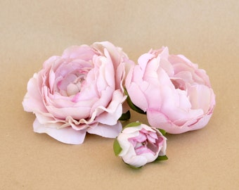 Puede incluir: Tres capullos de flores de seda rosa con tallos verdes. Las flores están dispuestas sobre un fondo marrón.