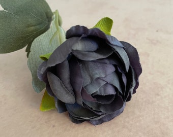 May include: A single dark purple artificial rose with green leaves.