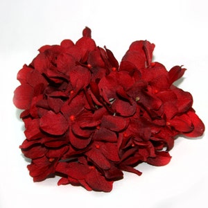May include: A cluster of deep red artificial hydrangea flowers. The flowers are made of fabric and have a realistic appearance.