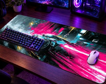 May include: A rectangular desk mat featuring a vibrant graphic print of a sports car in motion with streaks of bright pink, cyan, and dark blue colors. The mat is positioned on a wooden surface with a black mechanical keyboard and a white computer mouse.