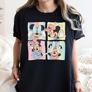 May include: Black t-shirt with a colorful graphic of four different images of Mickey Mouse. Each image shows Mickey Mouse with a different expression and pose.