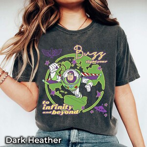 Puede incluir: Camiseta gris jaspeado oscuro con un dise&ntilde;o de Buzz Lightyear de Toy Story. El dise&ntilde;o incluye a Buzz Lightyear con un traje espacial verde y blanco, las palabras "Buzz Lightyear" y la frase "to infinity and beyond".