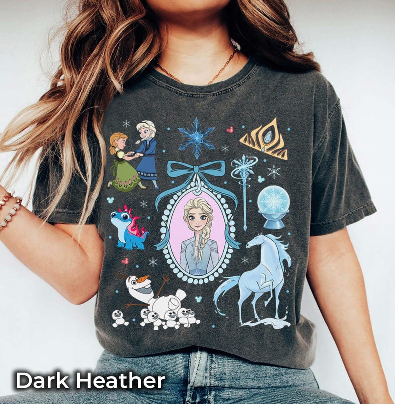 May include: Dark heather grey t-shirt featuring a graphic of Elsa from Frozen, surrounded by other characters and symbols from the movie. The shirt includes the text "Dark Heather" at the bottom.