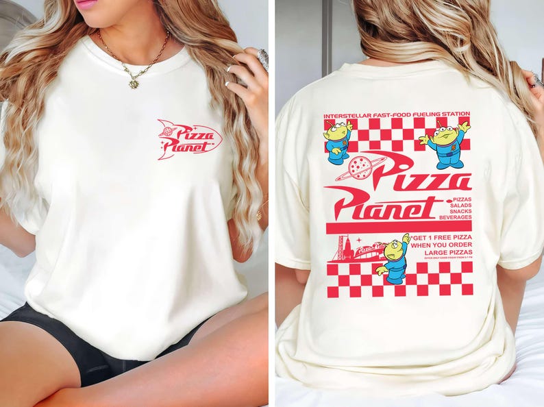 May include: Cream-colored t-shirt with red Pizza Planet logo on the front and back. The back features the text "Interstellar Fast-Food Fueling Station" and cartoon aliens. The shirt also has the text "Pizzas, Salads, Snacks, Beverages".